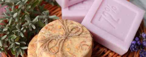 Bars of natural soap on wicker mat, on wooden background